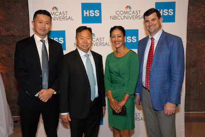 Four people stand in front of HSS banner