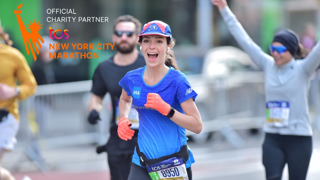 Photo of marathon runner smiling pointing at HSS sign