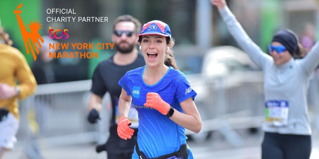 Photo of marathon runner smiling pointing at HSS sign
