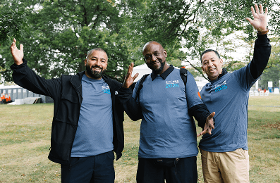 Volunteer smiling and raising her arms with pom poms